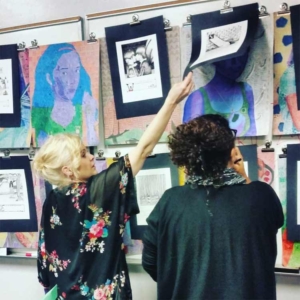 Leigh Preuss and student hanging artwork